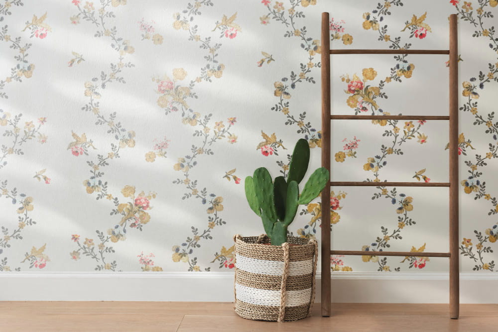 Transformez Votre Intérieur : L’Éclat et le Charme Intemporel d’un Papier Peint Panoramique Floral Un mur décoré d'un élégant papier peint panoramique à motifs floraux et ramages, avec un cactus dans un panier et une échelle décorative
