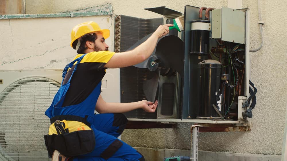 Un professionnel utilisant les "outils essentiels du frigoriste" pour l'entretien d'une unité de climatisation extérieure, garantissant son bon fonctionnement