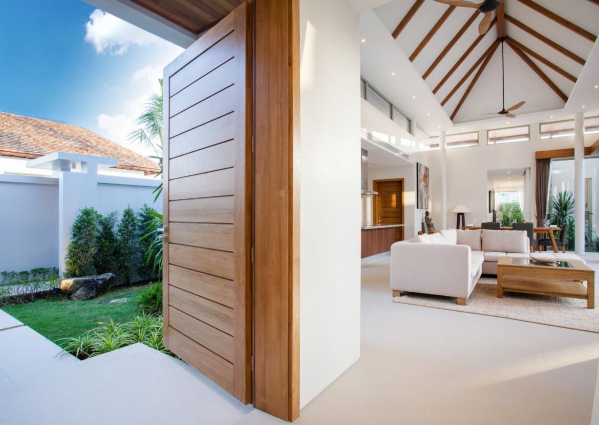 Grande porte pivotante en bois ouverte sur un salon moderne.