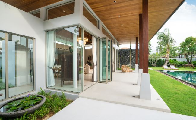 Entrée de maison moderne avec portes en bois et jardin tropical.