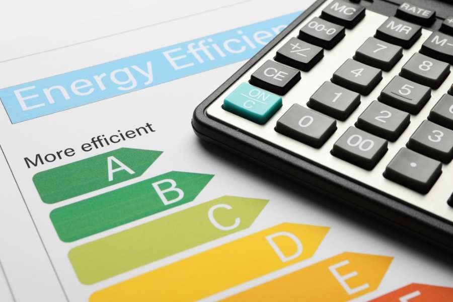 Une calculatrice posée sur un document présentant des étiquettes d'efficacité pour réduire votre facture énergétique.