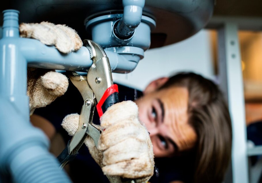 Réparation d'un siphon d'évier en plastique avec une pince parmi les outils de base plomberie debutant